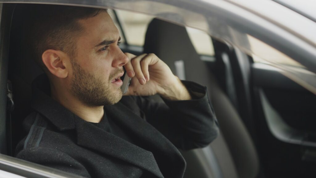 Man talking on phone inside a car.